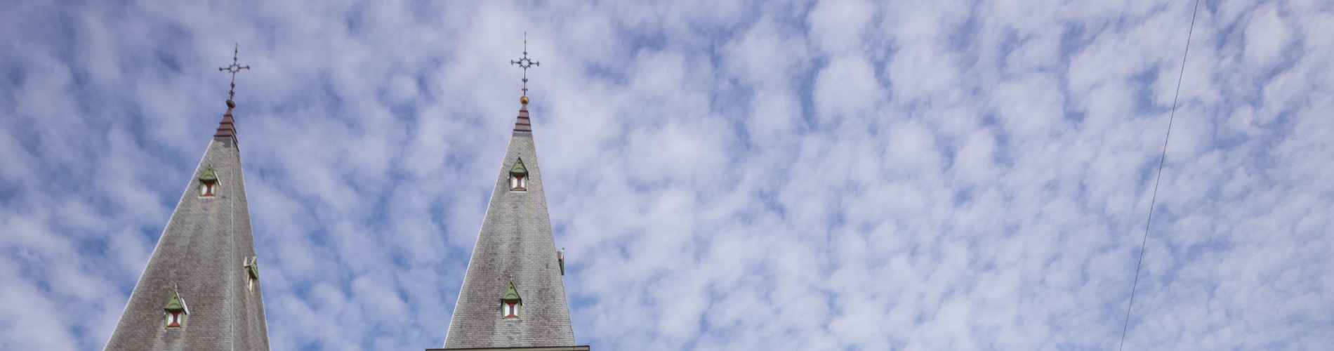 Historisch gebouw met torens en een wolkenlucht op de achtergrond.